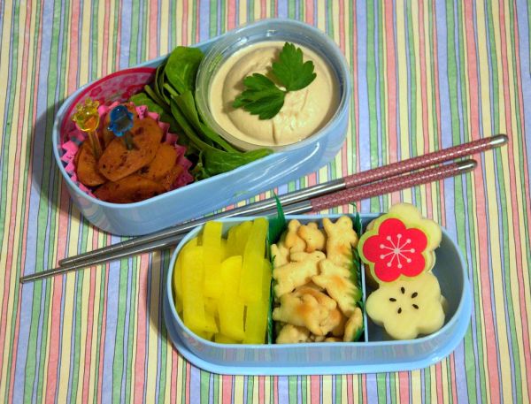 Hands using chopsticks to pick up a side dish from a shared plate